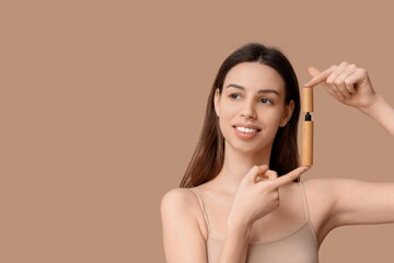 Fototapeta premium Portrait of beautiful young woman with mascara on brown background