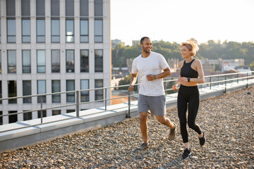 Happy man and woman jogging outdoors to maintain healthy body and mind. Young sports couple doing...