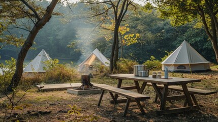 A well-equipped outdoor kitchen setup with wooden table and chairs, complemented by a group of field tents in a camping area