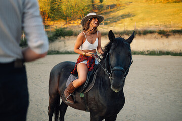 Young attractive smiling cowgirl is horseback riding at homestead.