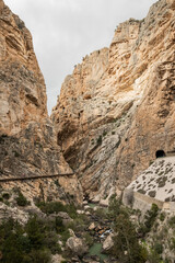 Fototapeta premium hiking trail caminito del rey, kings walkway, in Malaga Spain. narrow footpath leads through natural beauty mountain range cliff faces of gaitanes gorge. hisotric landmark popular tourist attraction