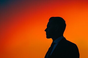 A silhouette of a man standing in front of a vivid orange sunset, sharply outlined against the colorful sky