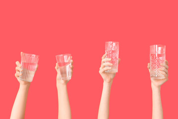 Female hands with different glasses of water on red background, closeup