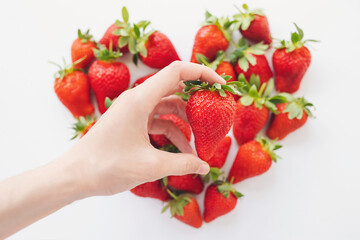 strawberry in hand on blurred Heart made from strawberry, on white background. Fruits diet, Love...