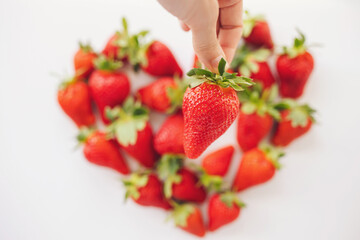 strawberry in hand on blurred Heart made from strawberry, on white background. Fruits diet, Love...