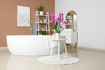 Interior of bathroom with sink, bathtub and orchid flower on table