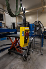 A yellow electric controller suspended from a crane in the workshop.
