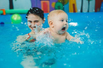 Swimming pool for babies. A baby learns to swim with a coach
