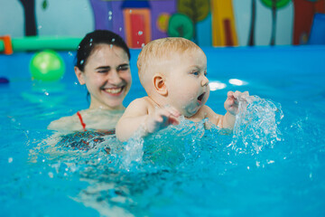 Swimming pool for babies. A baby learns to swim with a coach