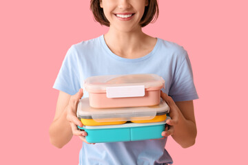 Beautiful young happy woman with lunchboxes of tasty food on pink background, closeup