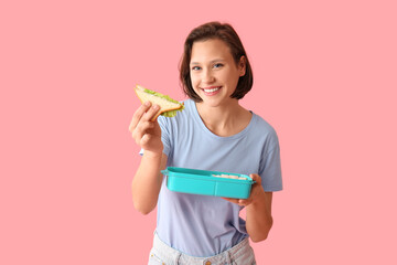 Beautiful young happy woman with sandwich and lunchbox of tasty food on pink background