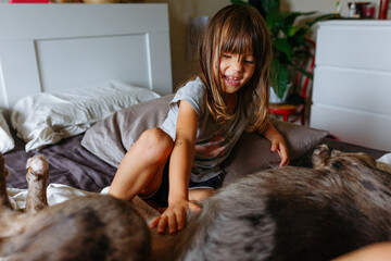 smiling child and dog lying on the bed and playing together