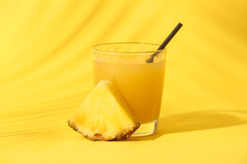 Glass of fresh tasty pineapple juice on yellow background