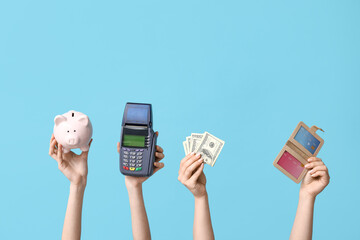 Female hands with credit cards, money, piggy bank and payment terminal on blue background