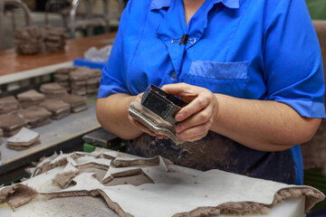 A shoe factory worker cuts pieces of leather from a blank.