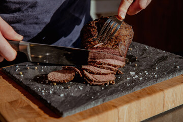 Steak cut into thin pieces and slices on a dark background