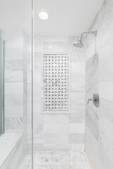 A shower with marble subway and hexagon tiles, an interlocking tile pattern on the wall, bench...