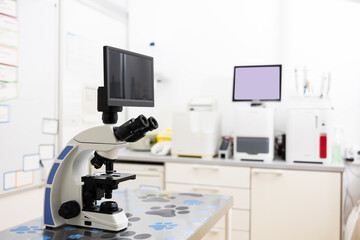 Modern digital trinocular microscope standing on table in veterinary clinic laboratory for detailed...
