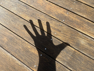 Shadow of a hand on wooden deck