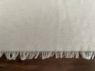 Light-colored fabric with frayed edge on wooden surface
