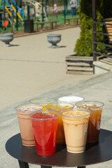 Takeaway glasses of summer drinks with ice. Lemonades and coctails on the table