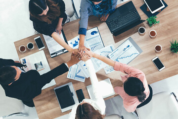 Businessmen and businesswomen joining hands in group meeting at multicultural office room showing...