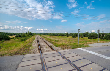 Przejazd kolejowy - tory biegnące przez las i łąki pod błękitnym niebem. Piękne i słoneczne letnie popołudnie wśród natury na skraju Ożarowa (woj. świętokrzyskie). © Grzegorz