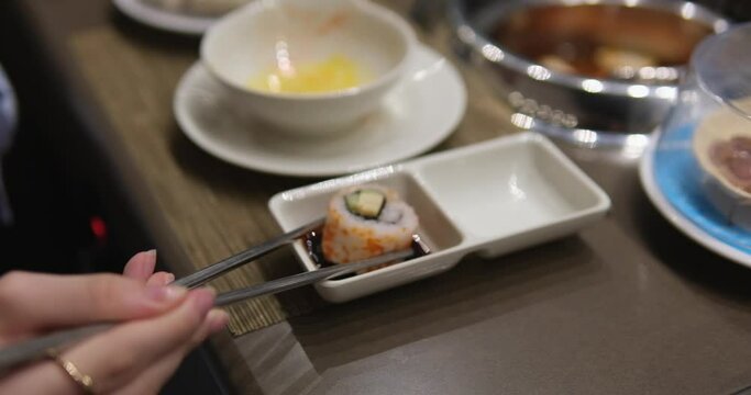Plates pass by to choose dishes Asia buffet Young woman in an asian cafe cook food in a hot pot. Food is served on a conveyor on a little plates. Food conveyor.
