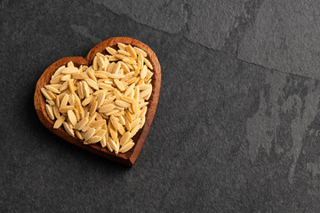 Dried orzo pasta in the heart shaped bowl - Italian risoni in the shape of rice grains