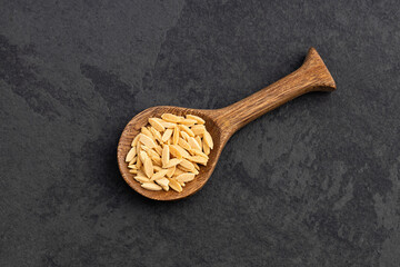 Italian dry risoni pasta - Raw Orzo on wooden spoon