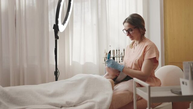A focused beautician in a naturally lit salon administers a facial treatment to a relaxed client, providing expert skincare in a serene spa setting.