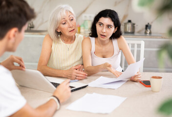 Young male insurance agent offers the best insurance terms for an elderly woman and her adult...