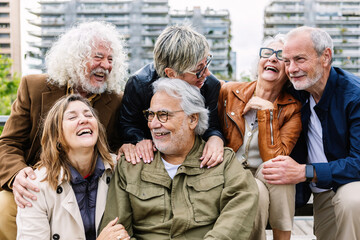Happy group of senior people laughing while sitting together outdoors. Elderly mature people