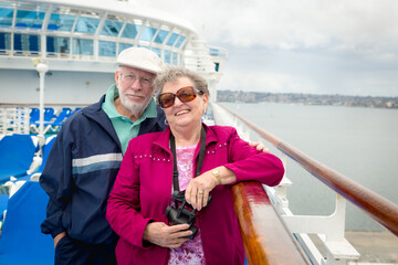 Senior Adult Couple Enjoying The View From Their Passenger Cruise Ship with Their Bonoculars.