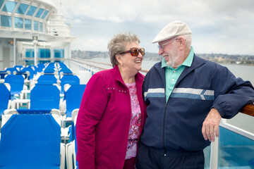 Senior Adult Couple Enjoying The View From Their Passenger Cruise Ship Railing.