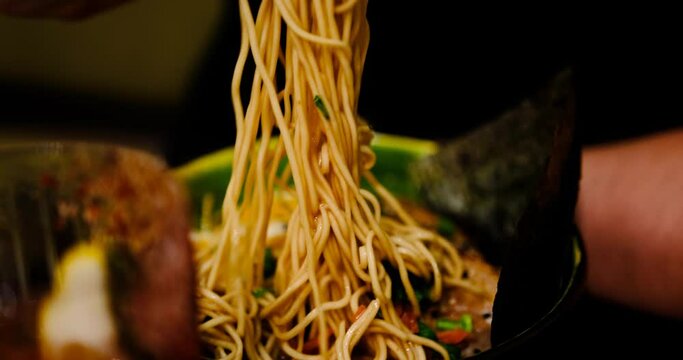 Man enjoys a delicious bowl of ramen, featuring corn, seaweed, noodles, eggs, and meat. Close-up shot captures the rich, nourishing soup, perfect for food enthusiasts seeking culinary inspiration.
