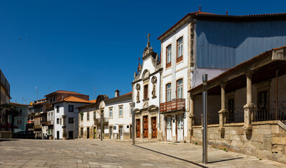 View of residential houses and ancient Church of Mercy on typical paved street in old town of Mirandela in spring, Portugal.