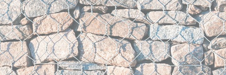 Wall of stones held by a metal mesh. Texture for background and design.