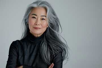 Mature asian white-haired woman posing with her arms crossed isolated over grey background