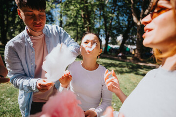 A group of friends enjoy a fun day at the park, laughing and sharing cotton candy on a sunny day, capturing a moment of joy and friendship.