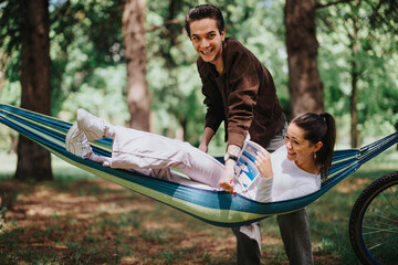 A young boy playfully teases a girl engrossed in a book while relaxing in a hammock, capturing a moment of joyful friendship in a lush park.