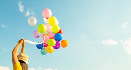 Hand holding multi colored balloons done with a retro vintage  filter effect. concept of festival, celebration, birthday, for background design.
