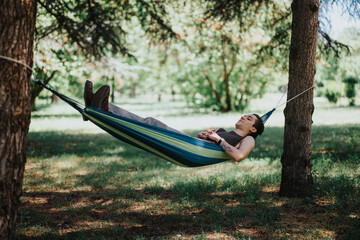 A serene moment as a young adult man unwinds in a colorful hammock, surrounded by the lush greenery of a tranquil park on a sunny day.