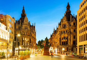 Evening view of illuminated Leysstraat street in Belgian city of Antwerp overlooking statue of...