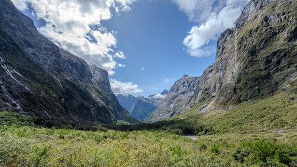 Canyon view in New Zealand South Island bright blue sky with scattered clouds. Towering cliffs frame the lush green valley. Concept of Outdoor, Nature, Travel, Background
