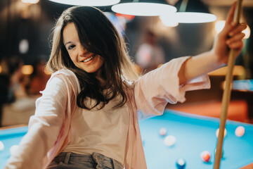 Smiling young woman having fun playing billiards with companions in a cozy bar atmosphere, showcasing a joyful night out.