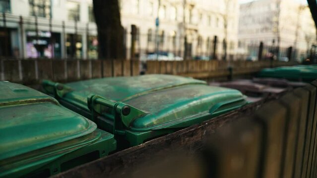 Row of green garbage cans lined up on the sidewalk