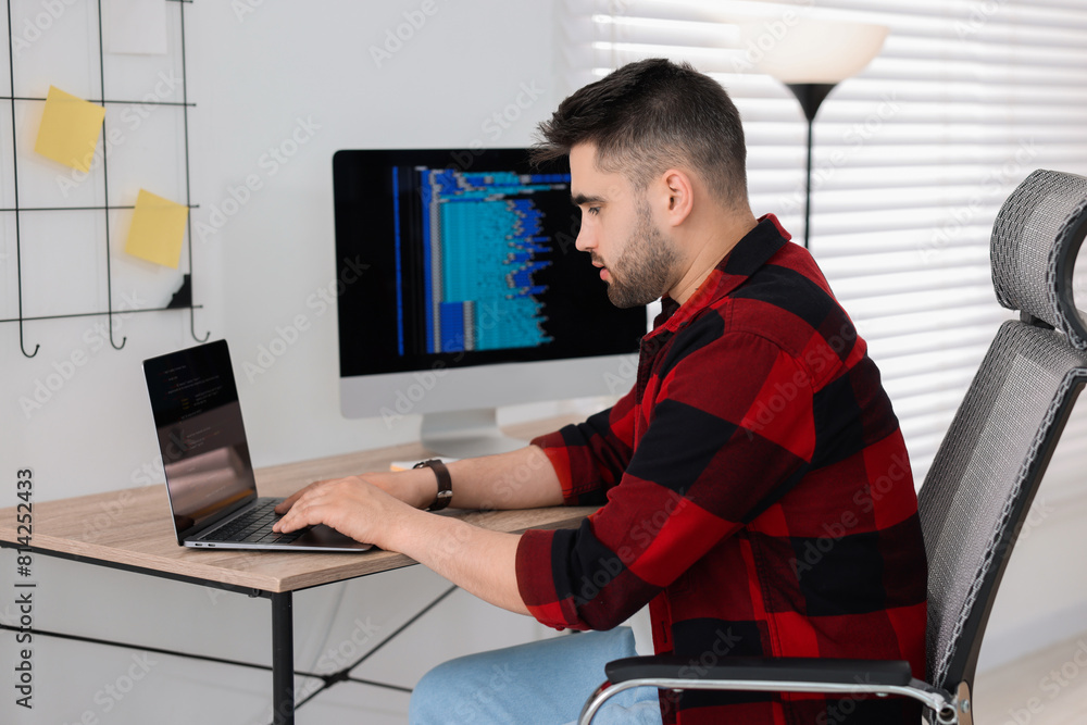 Poster young programmer working with laptop in office