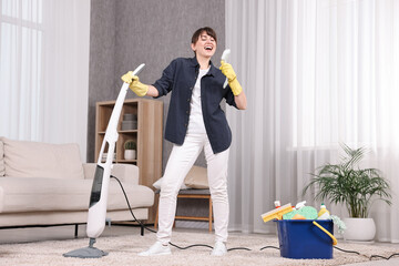 Happy young housewife having fun while cleaning carpet at home