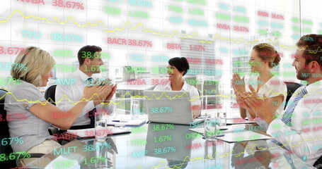 Image of trading board over diverse coworkers discussing reports and clapping in office